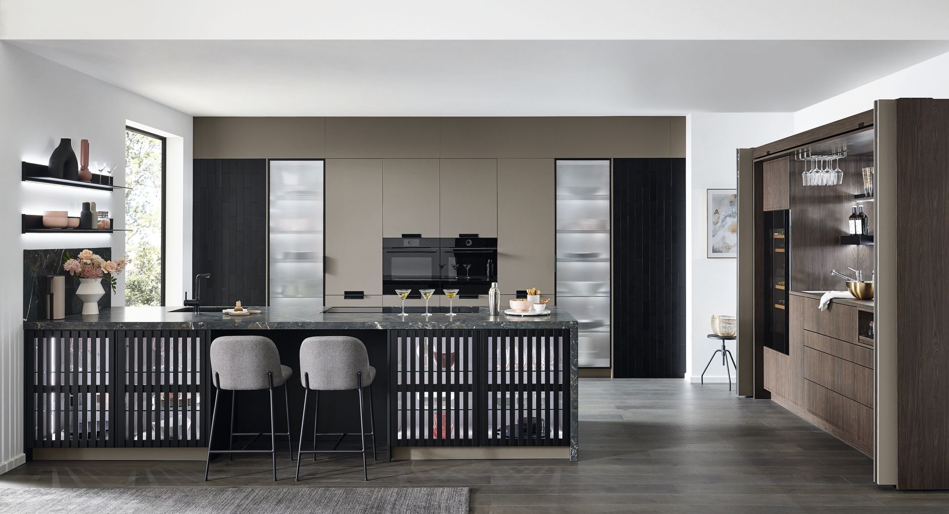 Cuisine avec armoires foncées, îlot central et appareils électroménagers intégrés.
