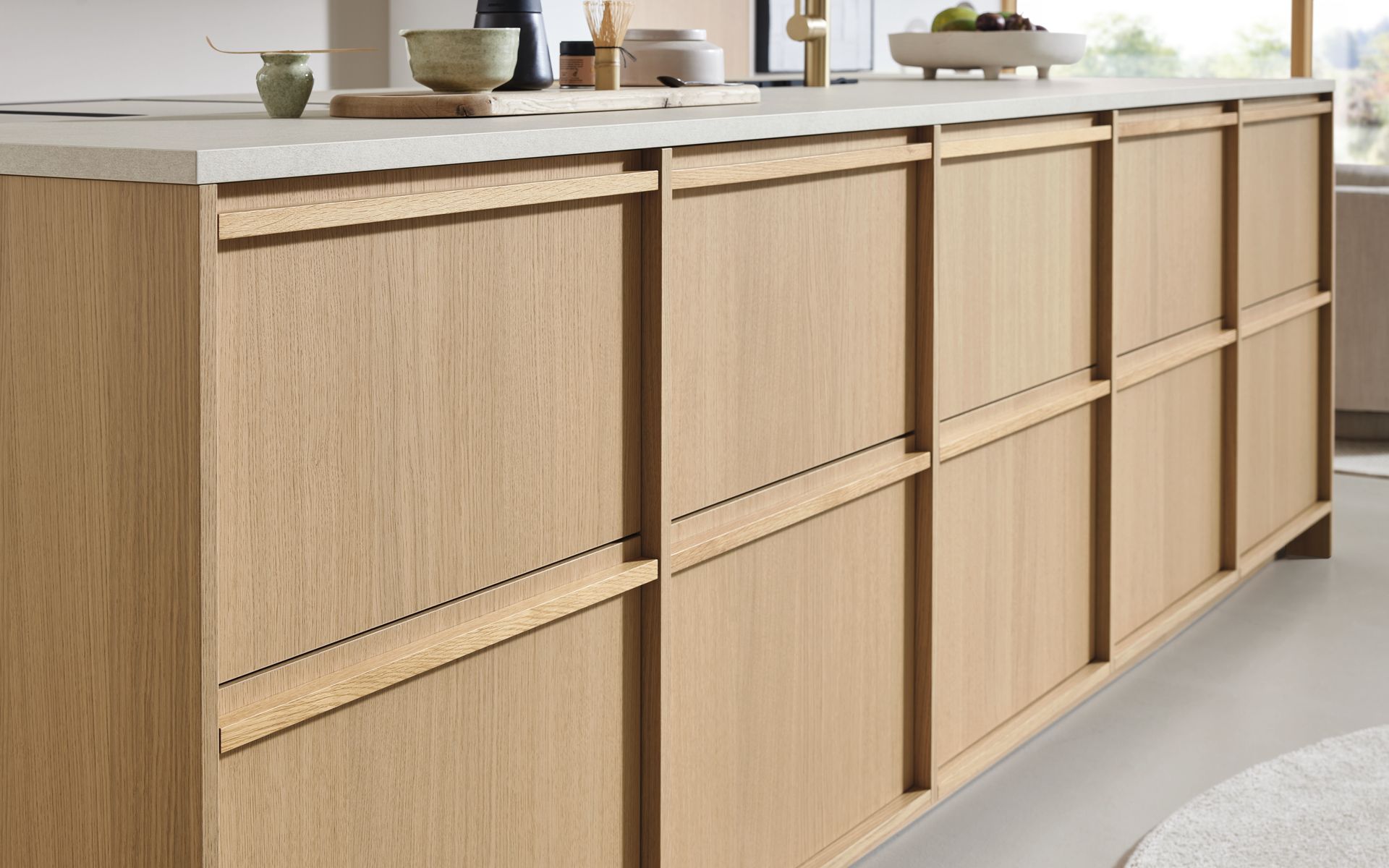 Meuble de cuisine en bois clair avec plan de travail blanc, vue en contreplongée.