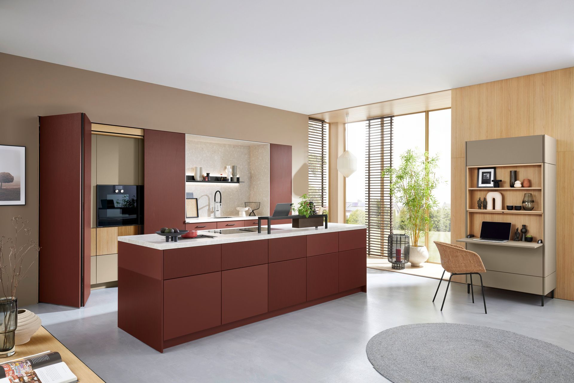 Cuisine moderne avec îlot couleur bordeaux, placards en bois clair et grandes fenêtres.