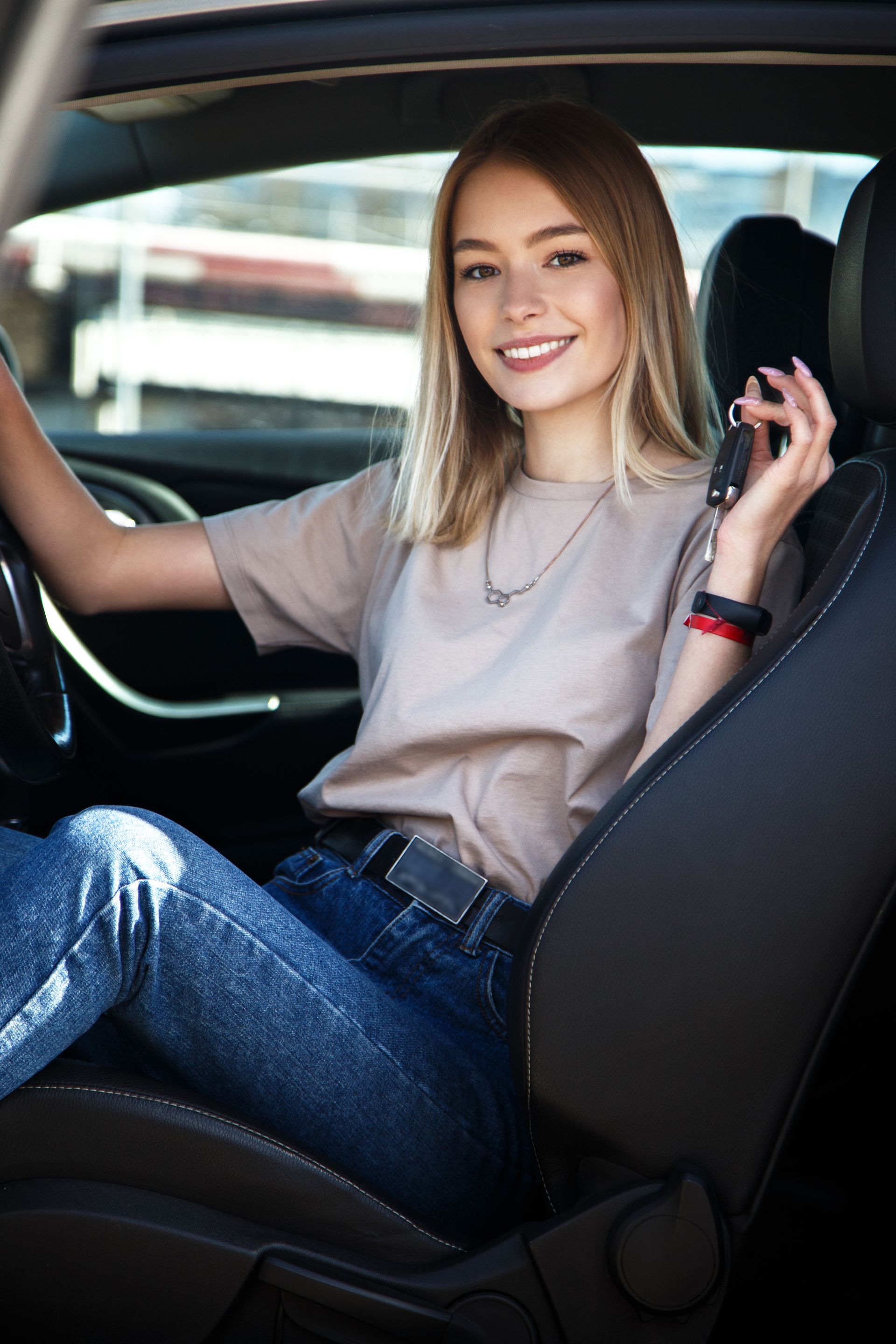 Femme souriante et heureuse dans une voiture avec des clés