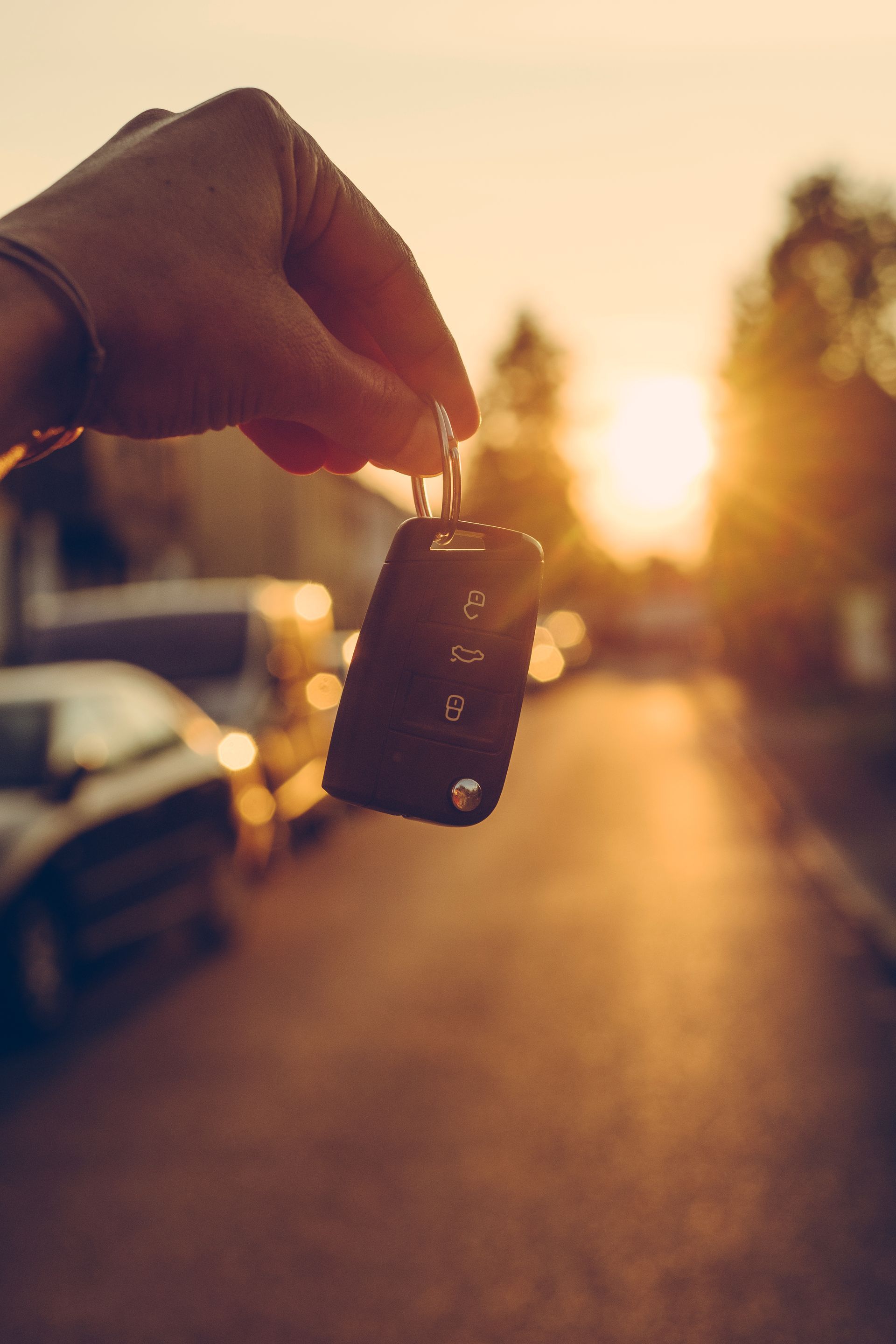 Une main tient une clé de voiture devant une route en contre-jour