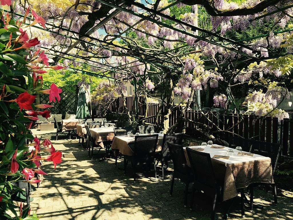 Photo d'une terrasse de restaurant fleurie avec des tables dressées.
