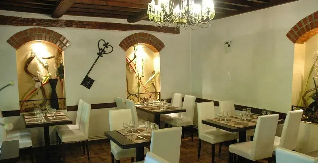 Photo d'une salle de restaurant avec des tables dressées et la clé du logo du restaurant posée sur le mur.