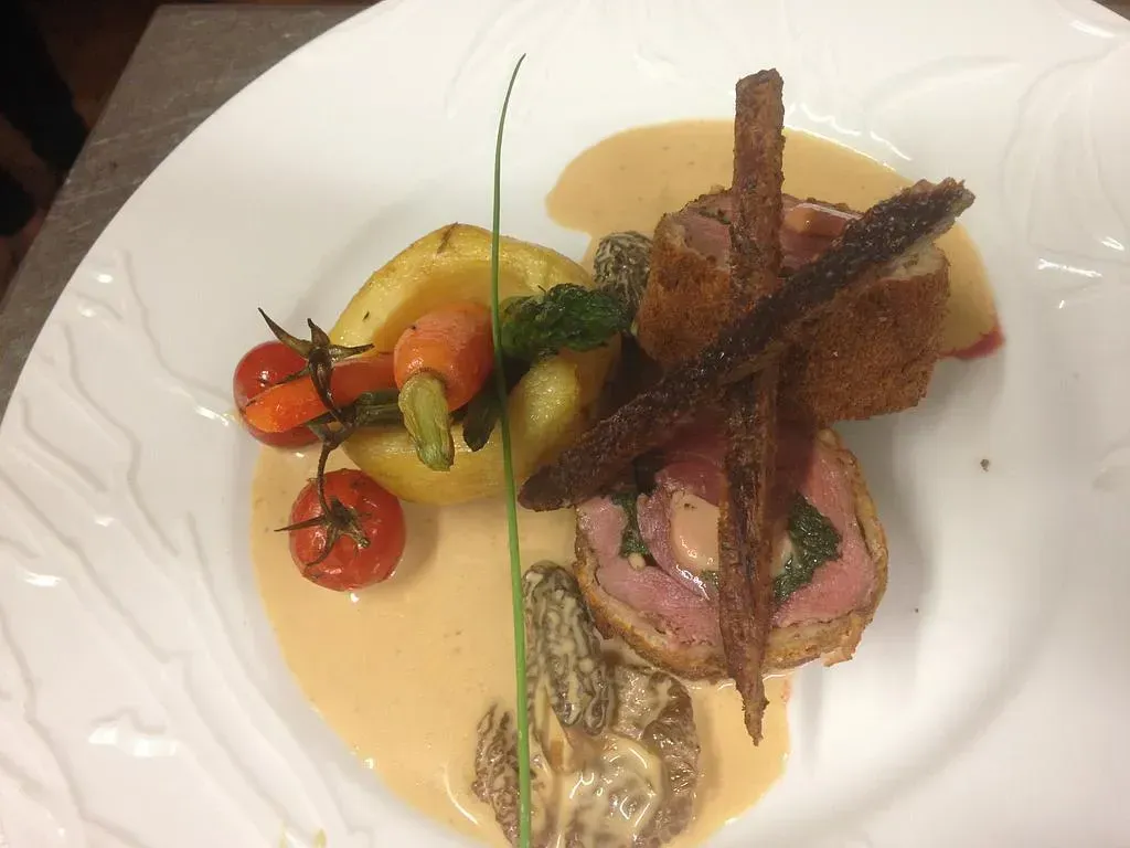 Photo d'un plat dressé avec de la viande, de la sauce, des pommes de terre, des carottes et des tomates cerises.