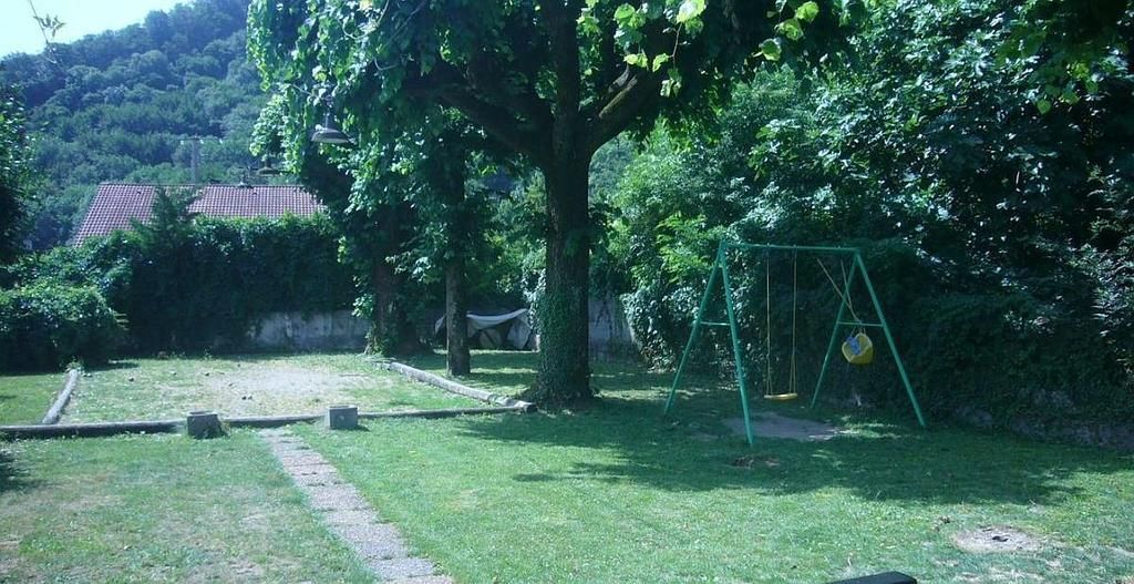 Photo de l'extérieur d'un restaurant avec un terrain de pétanque au fond et une balançoire.