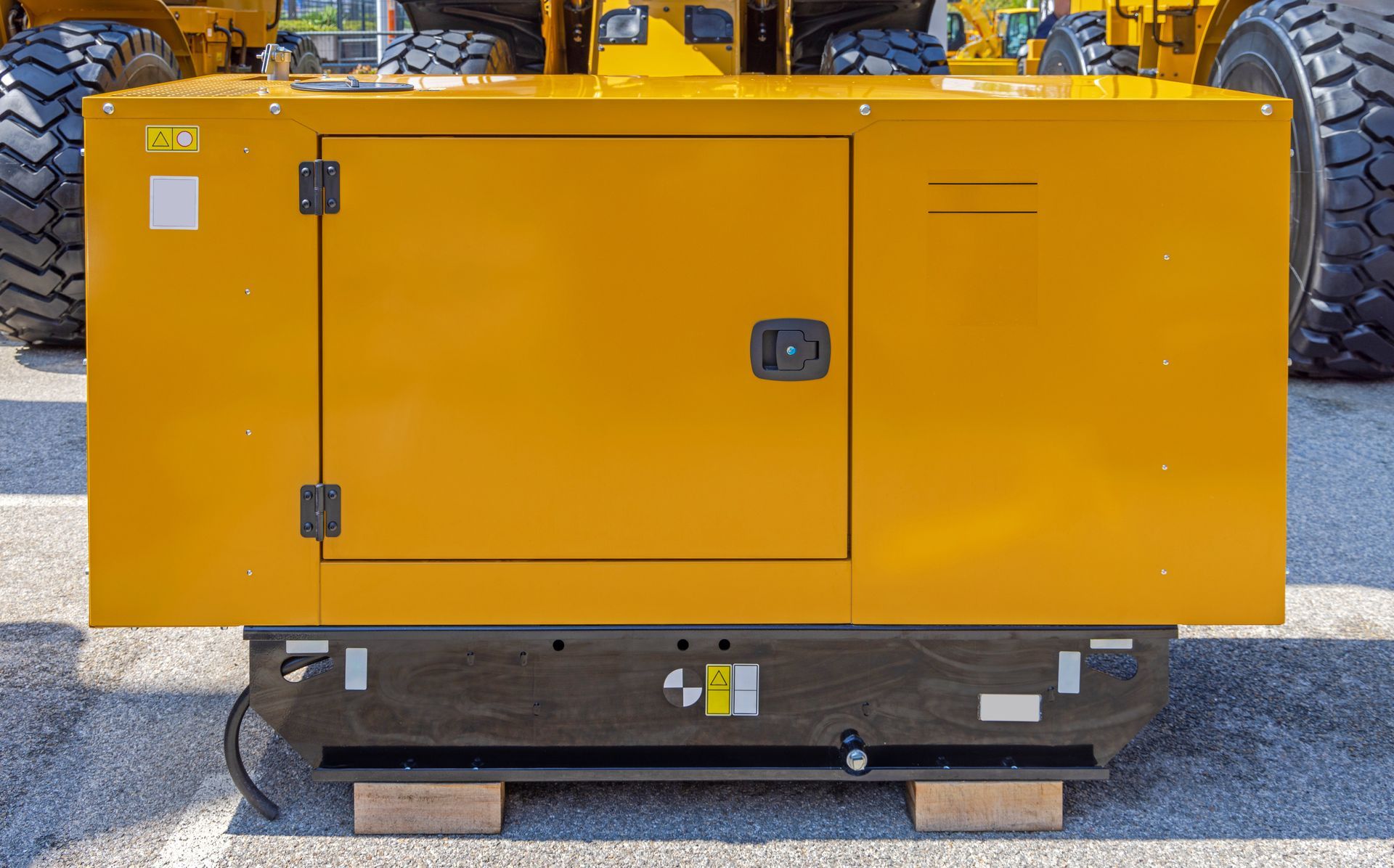 Générateur industriel jaune sur une palette à l'extérieur, avec portes d'accès et panneau de commande visibles.