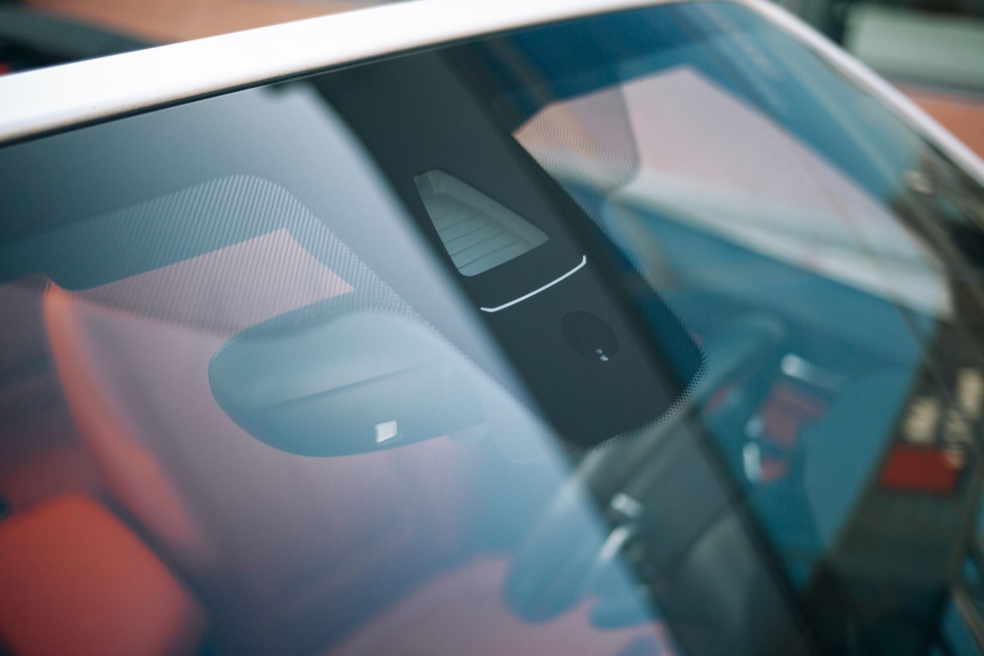 Gros plan sur un pare-brise de voiture reflétant l'environnement, avec le rétroviseur visible à l'intérieur.