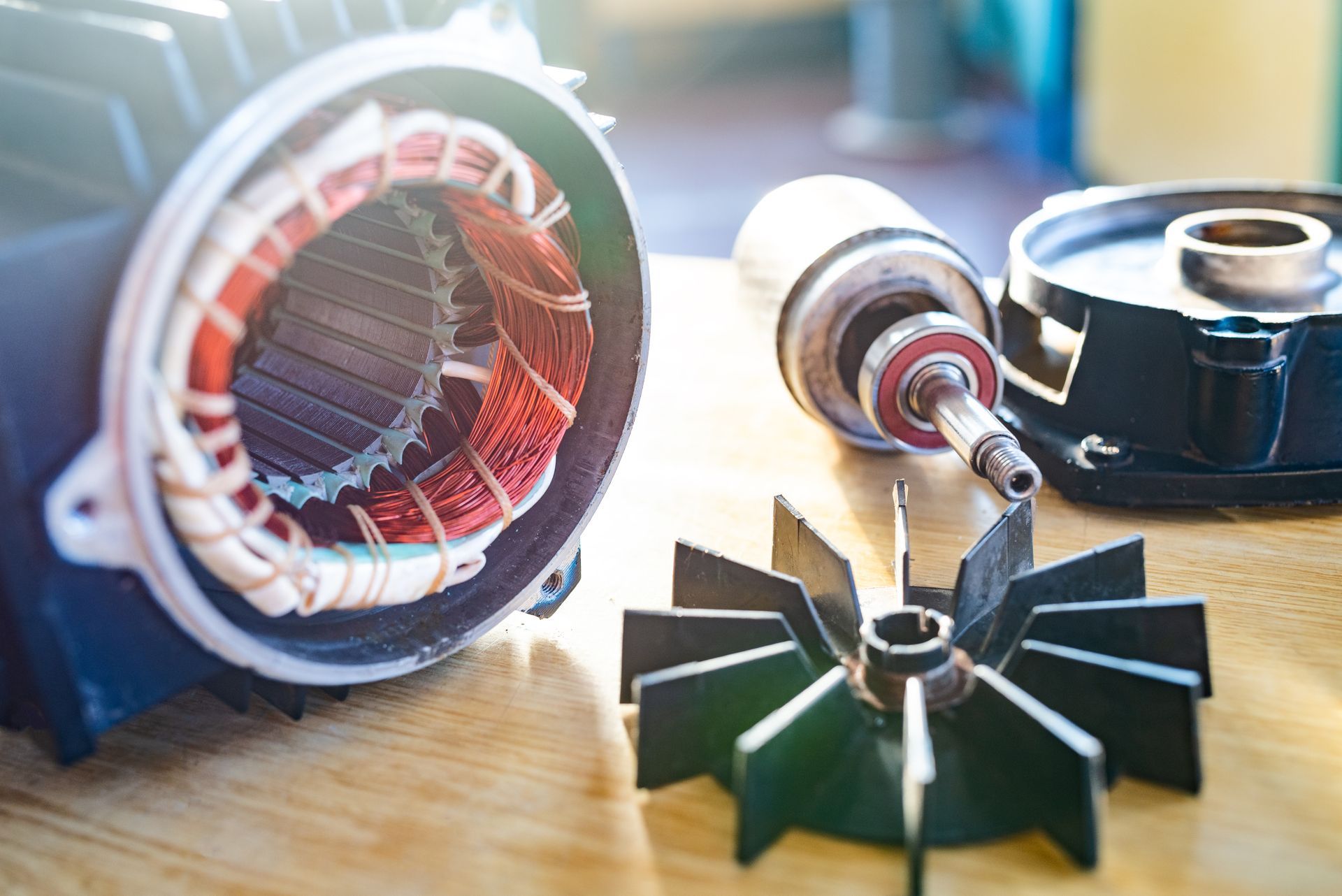 Pièces de moteur électrique sur un établi, notamment un stator, un rotor et des pales de ventilateur, dans un atelier