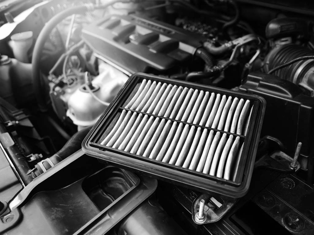 Moteur de voiture ouvert avec un filtre à air rectangulaire posé sur le dessus du compartiment moteur.
