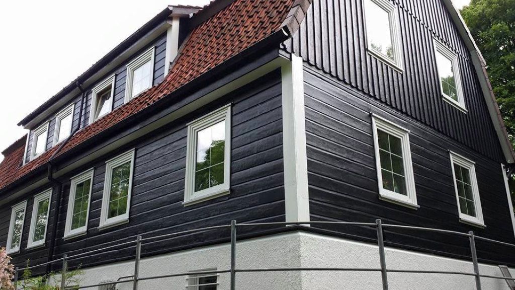 Ein schwarz-weißes Haus mit einem Ziegeldach