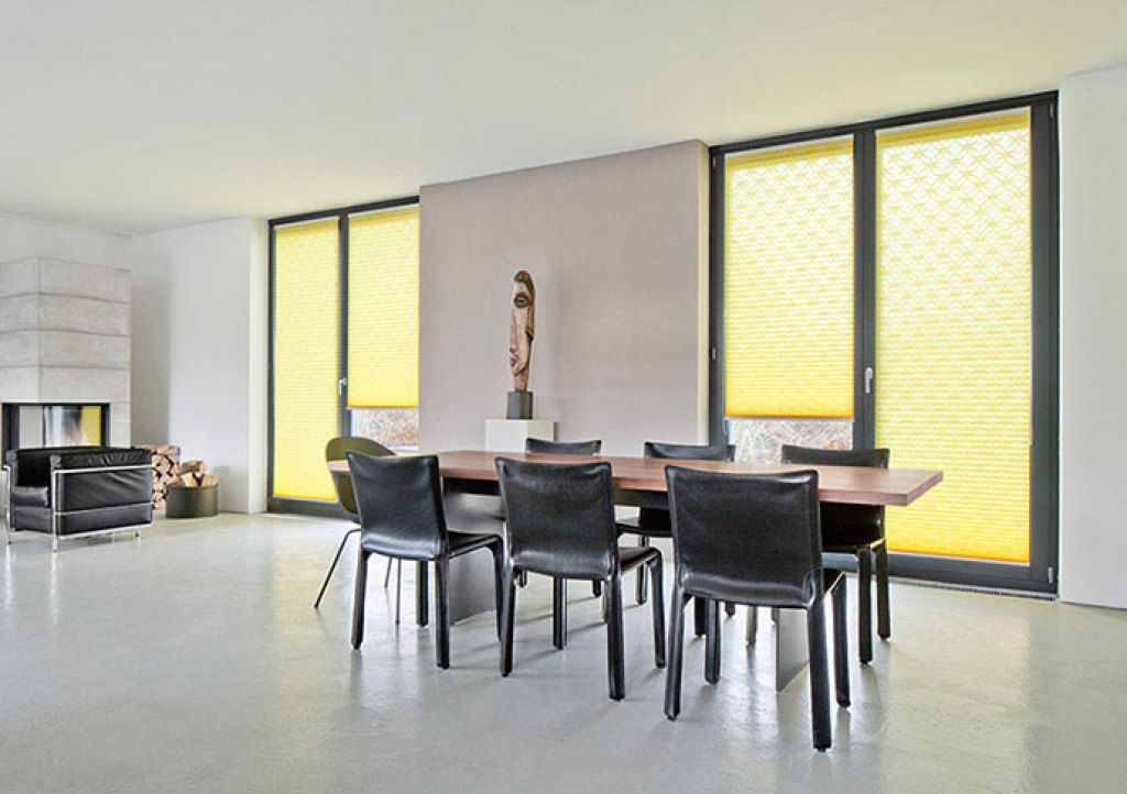 Ein Esszimmer mit Tisch und Stühlen und gelben Jalousien