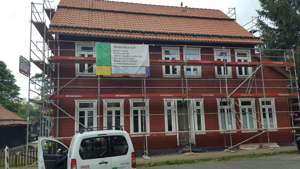 Ein weißer Lieferwagen parkt vor einem im Bau befindlichen Gebäude.