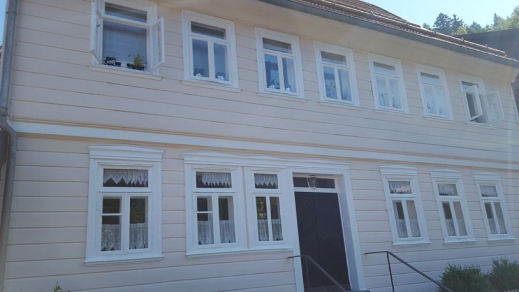 Ein großes weißes Haus mit vielen Fenstern und einer schwarzen Tür.