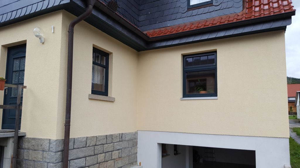 Ein Haus mit einer Garage und einer Dachrinne an der Seite.