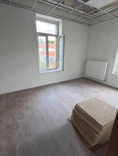 Pièce vide non meublée avec fenêtre, radiateur et planches empilées au sol