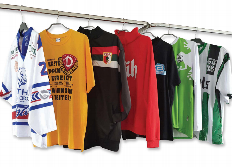 Ein Haufen T-Shirts hängen an einem Ständer, darunter eines mit der Aufschrift United