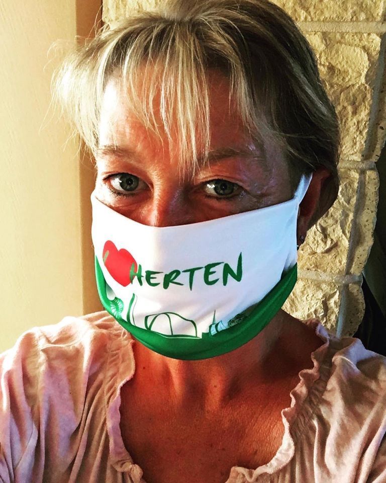 Eine Frau, die eine Gesichtsmaske mit der Aufschrift „Herten“ trägt