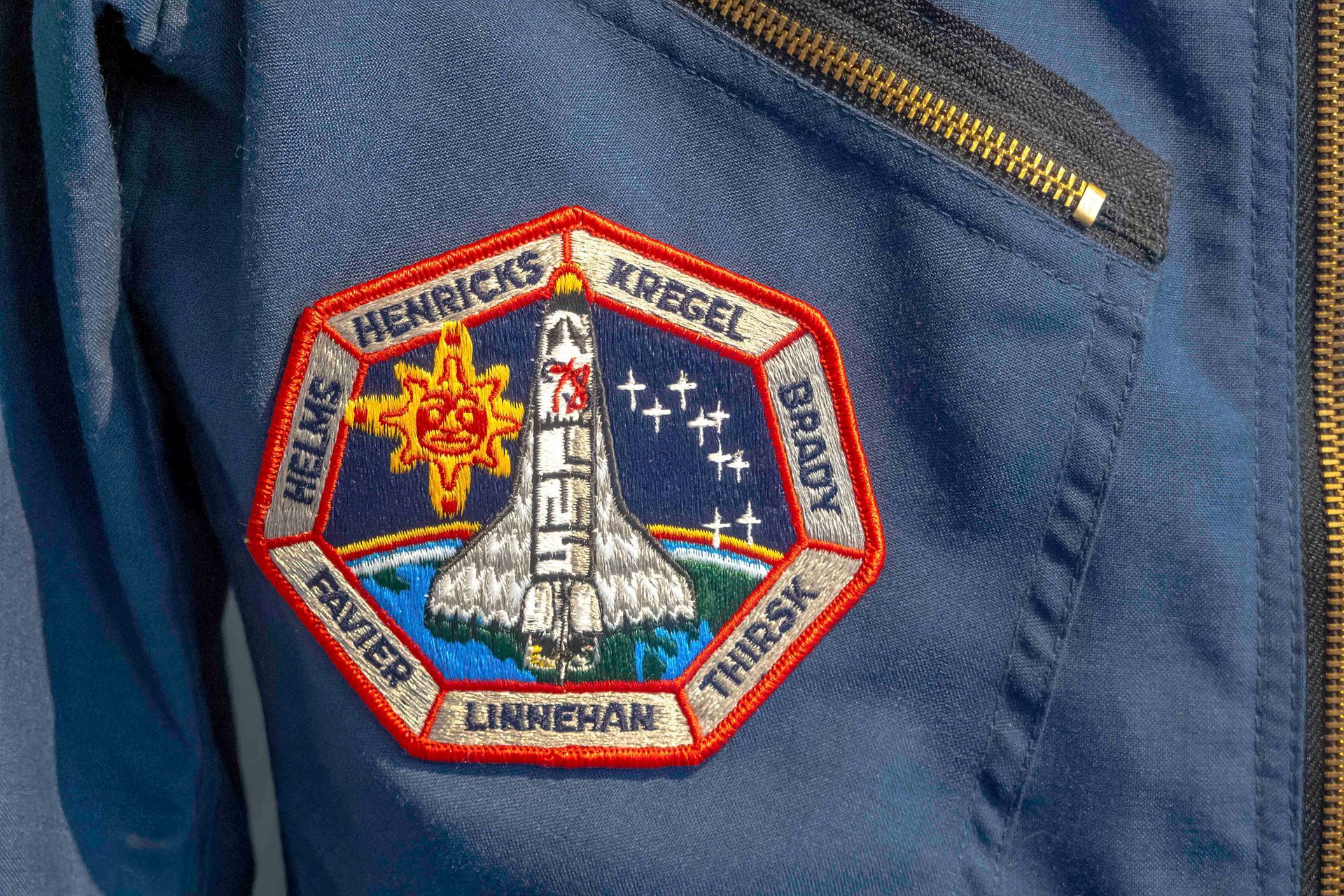 Ein Aufnäher an der Seite einer blauen Jacke mit einem Shuttle darauf.