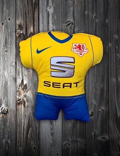 Ein gelbes Sitztrikot sitzt auf einer Holzoberfläche