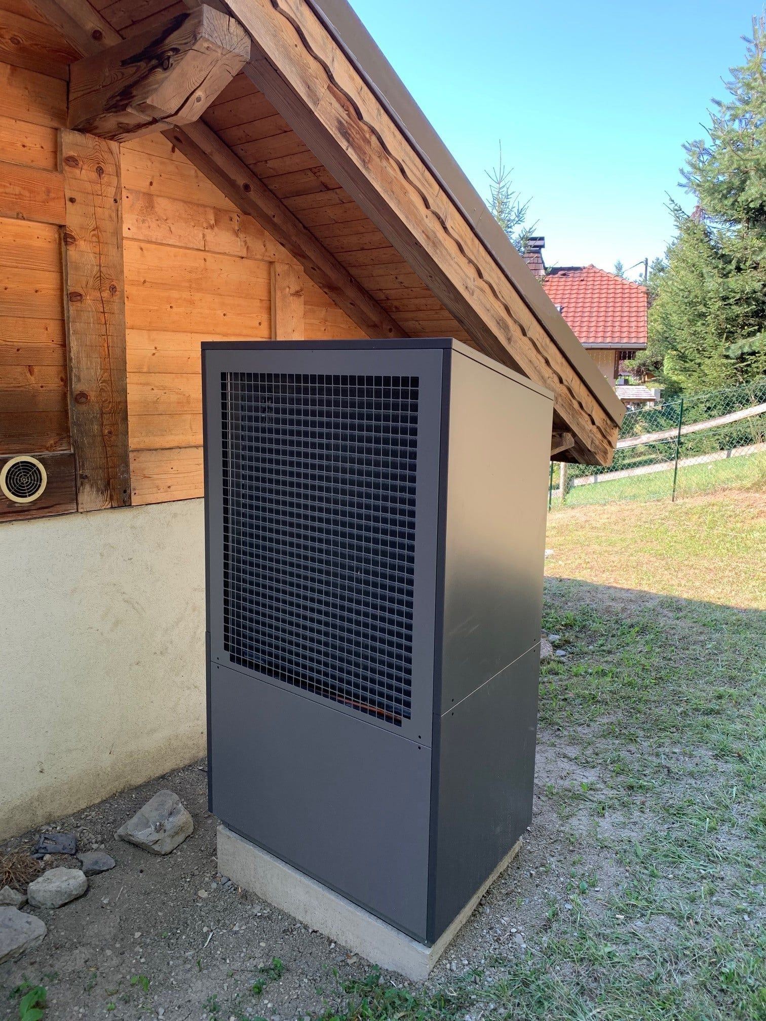 Pompe à chaleur esthétique en métal anthracite derrière un chalet
