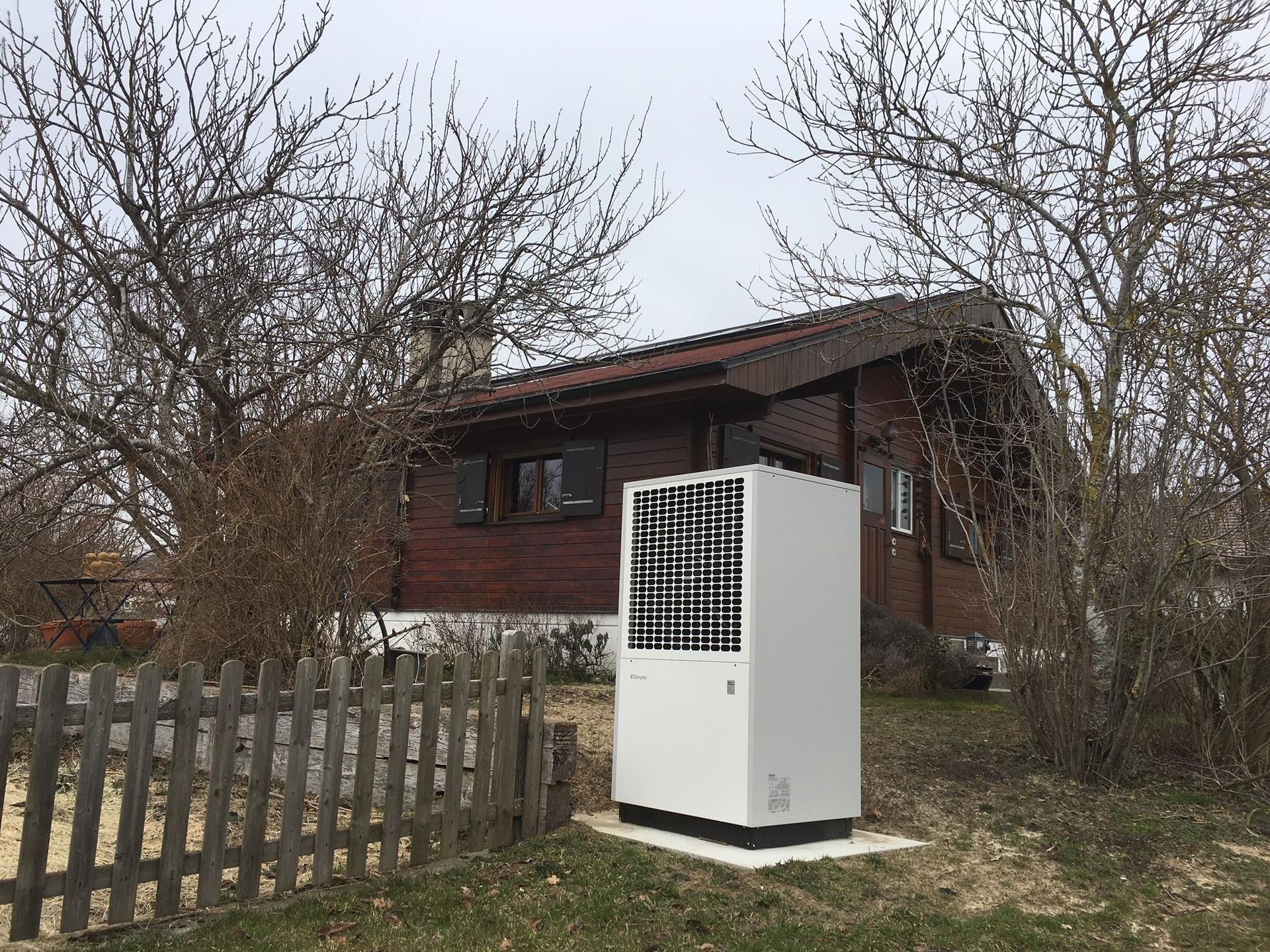 Pompe à chaleur esthétique en métal blanche dans le jardin d'un chalet de montagne