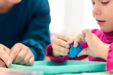 Kind bastelt mit blauer Knete