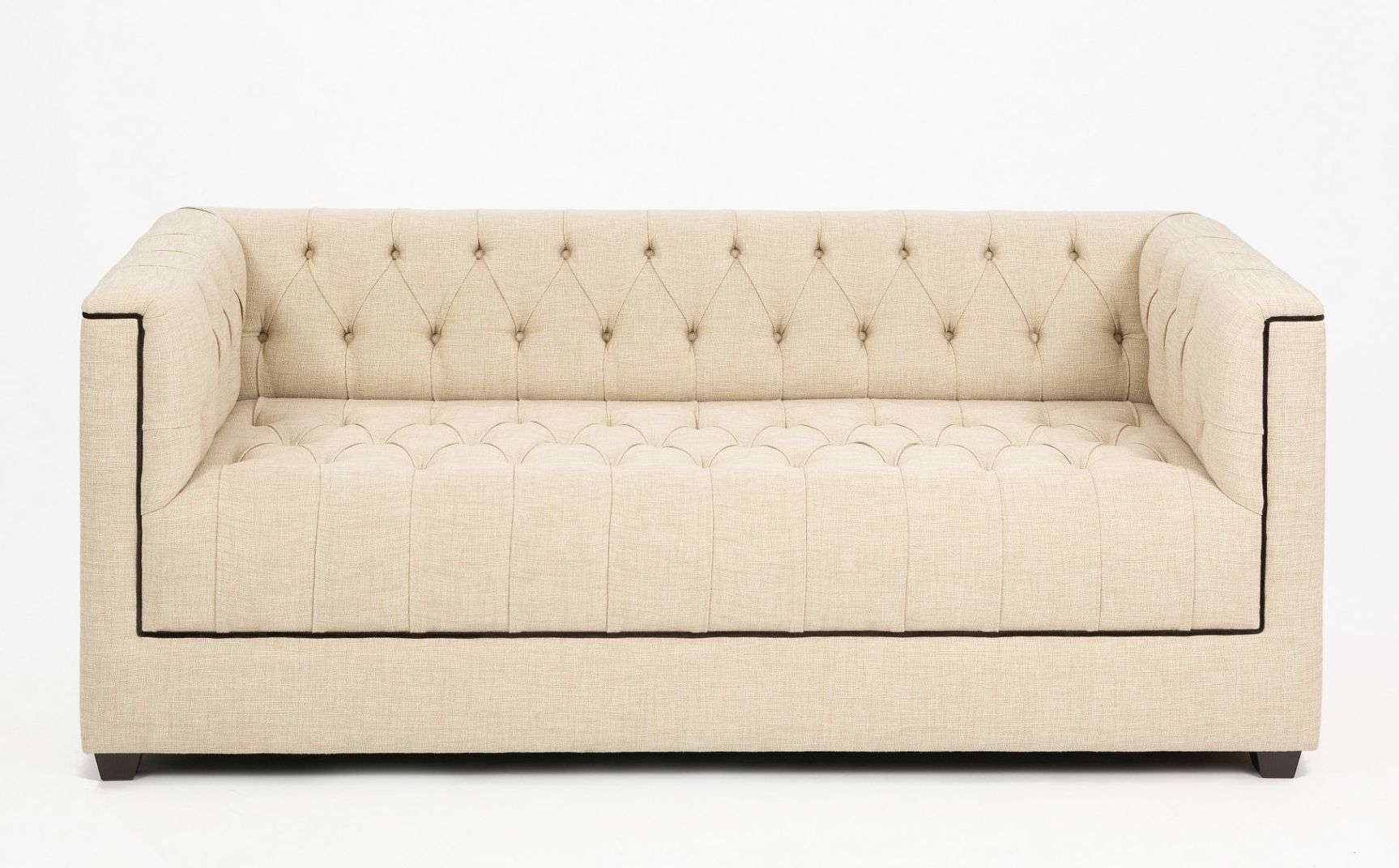Un sofá capitoné de color beige con ribete negro sobre un fondo blanco.