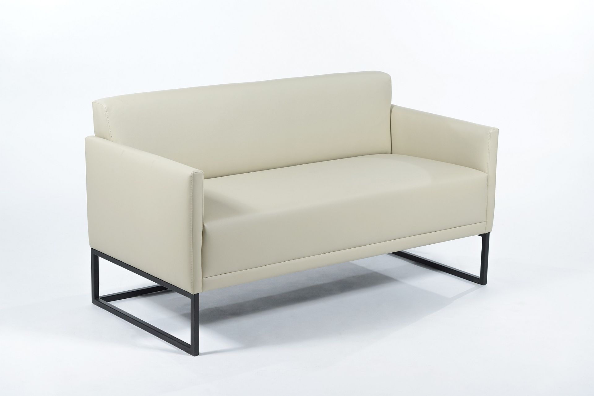 Un sofá blanco con patas negras está sentado sobre una superficie blanca.