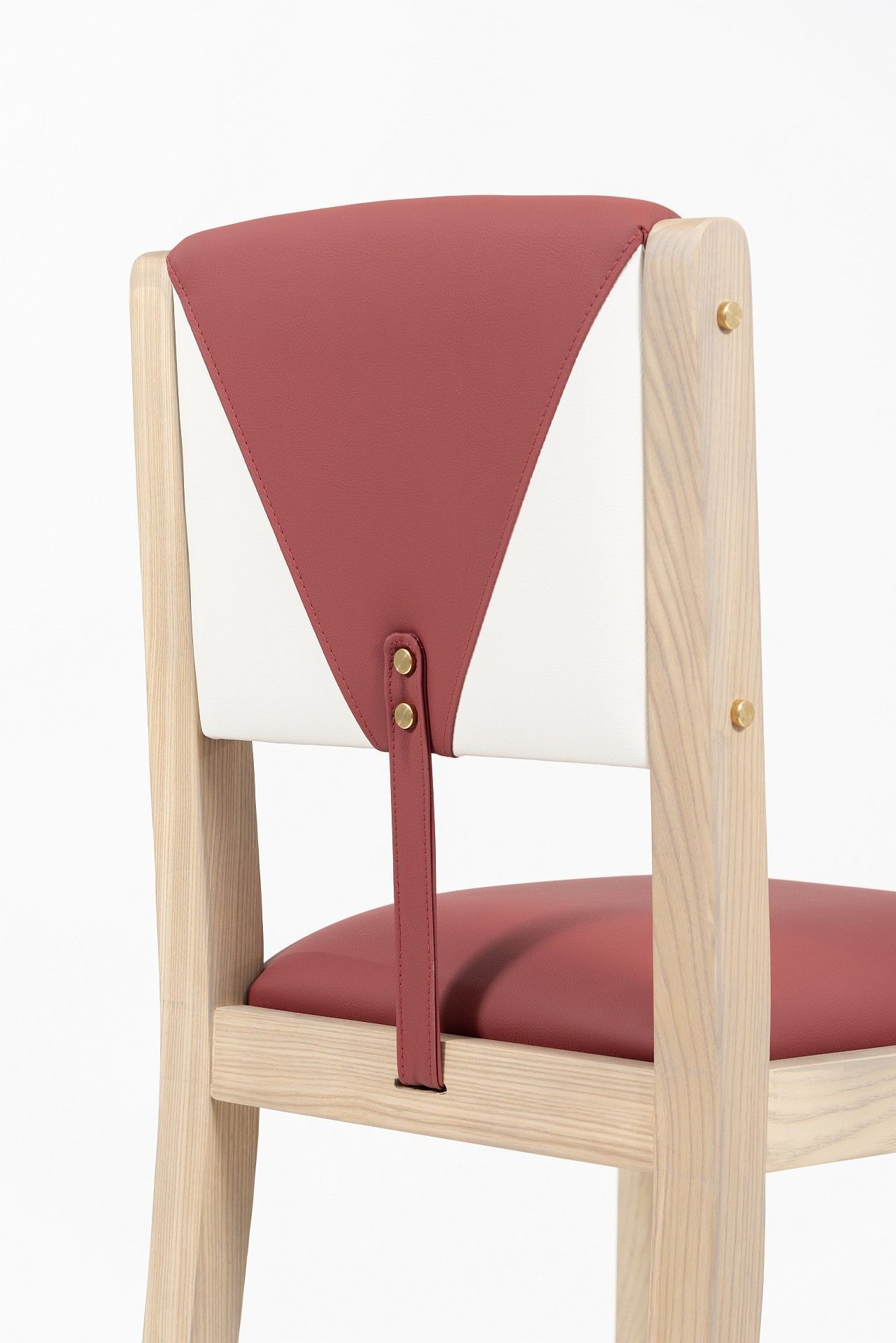 El respaldo de una silla de madera con un cojín rojo y blanco.