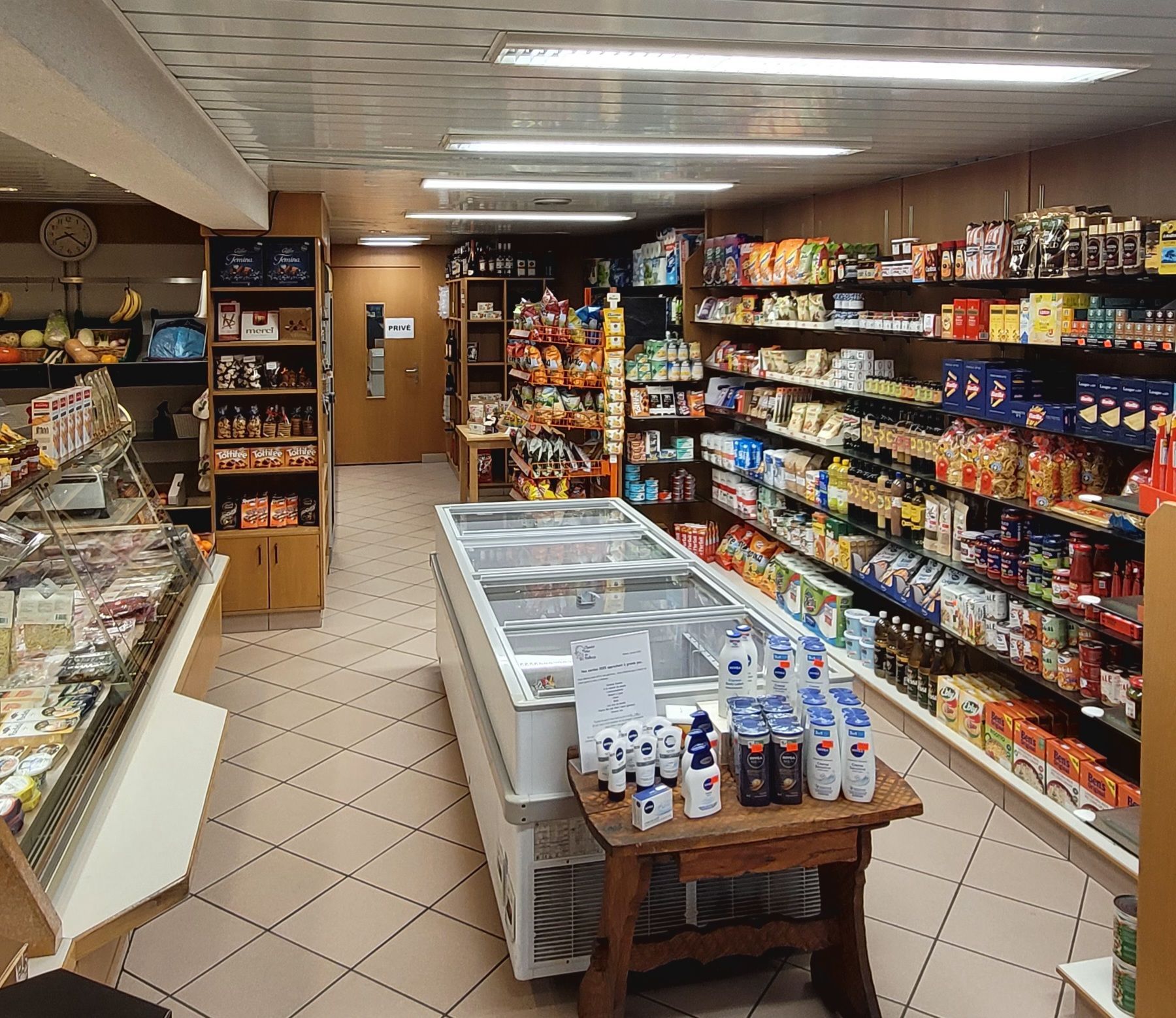 Une femme pousse un chariot rempli de nourriture dans un supermarché.