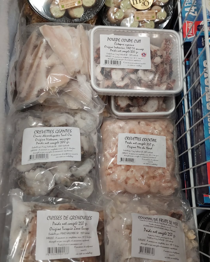 Une vitrine remplie de viande et de légumes dans une boucherie.