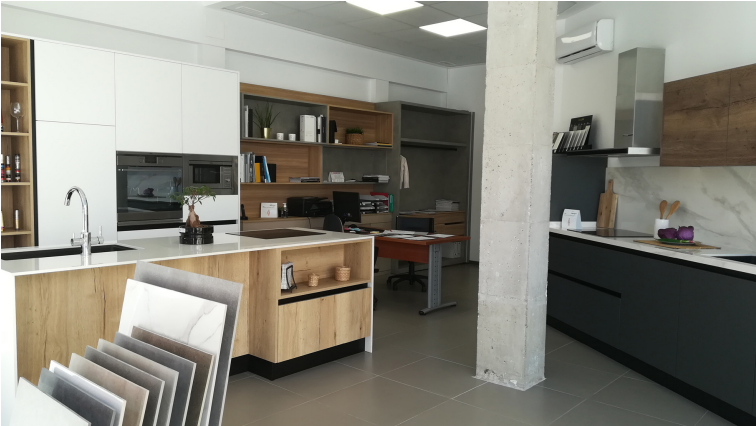 Interior de sala de exposición de cocina con exhibidores y área de oficina, que muestra diseños modernos.