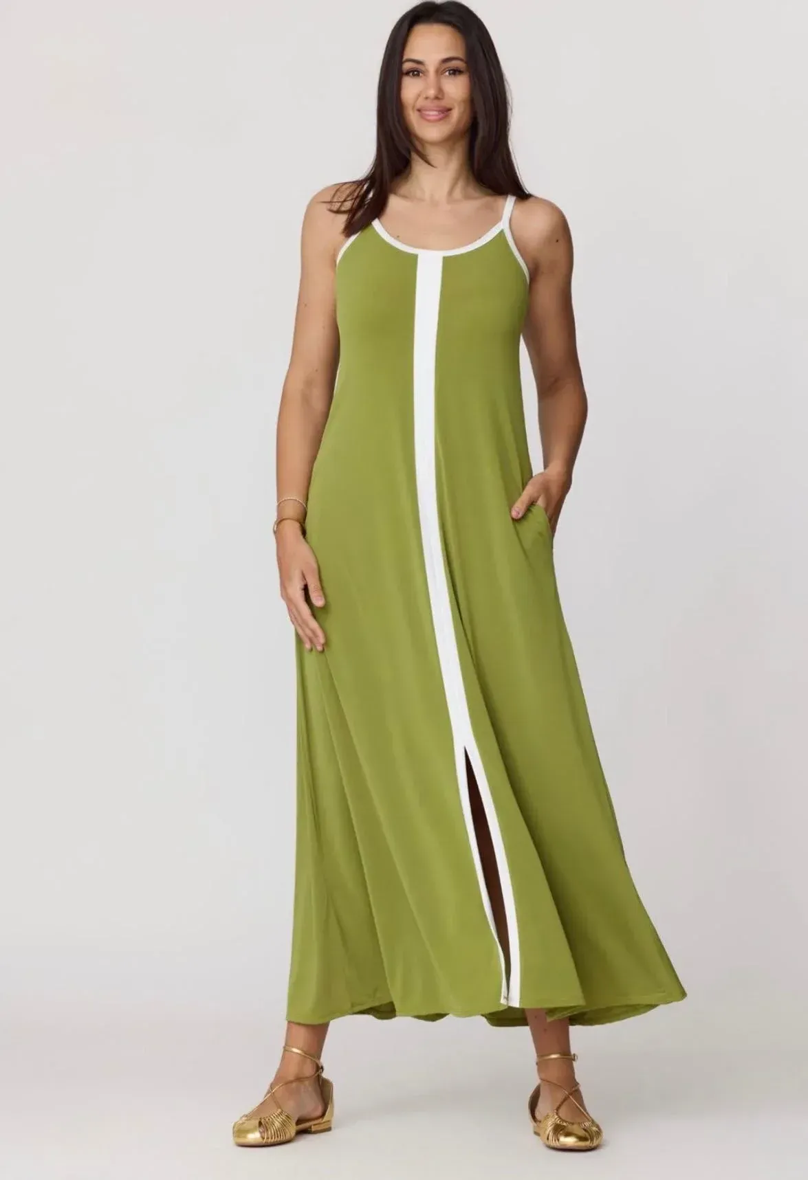 Mujer modelando un vestido verde lima sin mangas con ribete blanco y abertura frontal sobre un fondo liso.