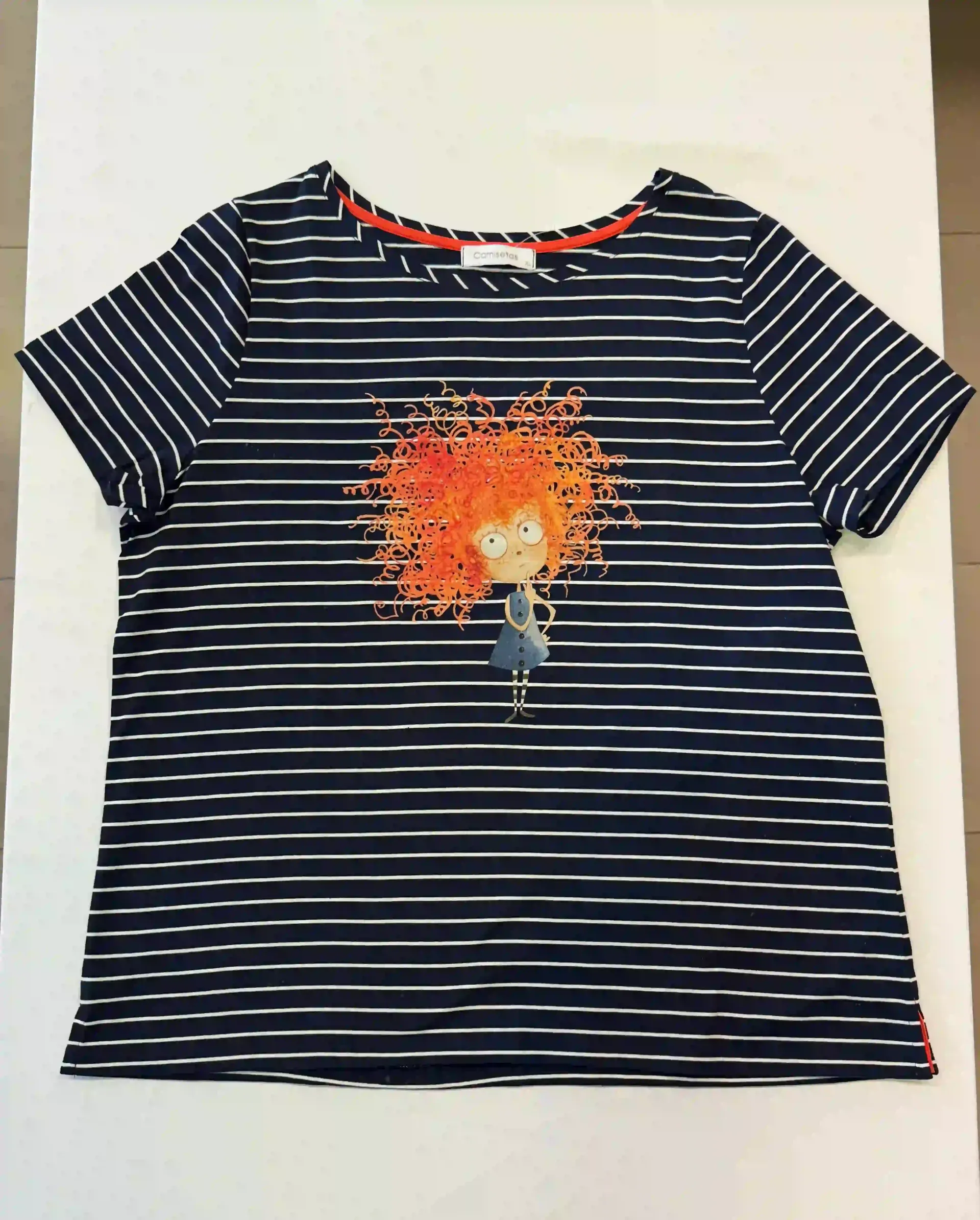 Camiseta de rayas azul marino y blancas con un gráfico abstracto naranja en el centro.