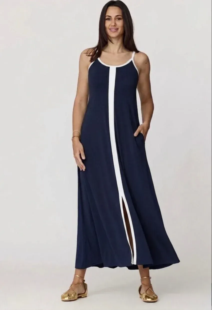 Mujer modelando un vestido largo azul marino con ribete blanco y abertura frontal, de pie sobre un fondo liso.
