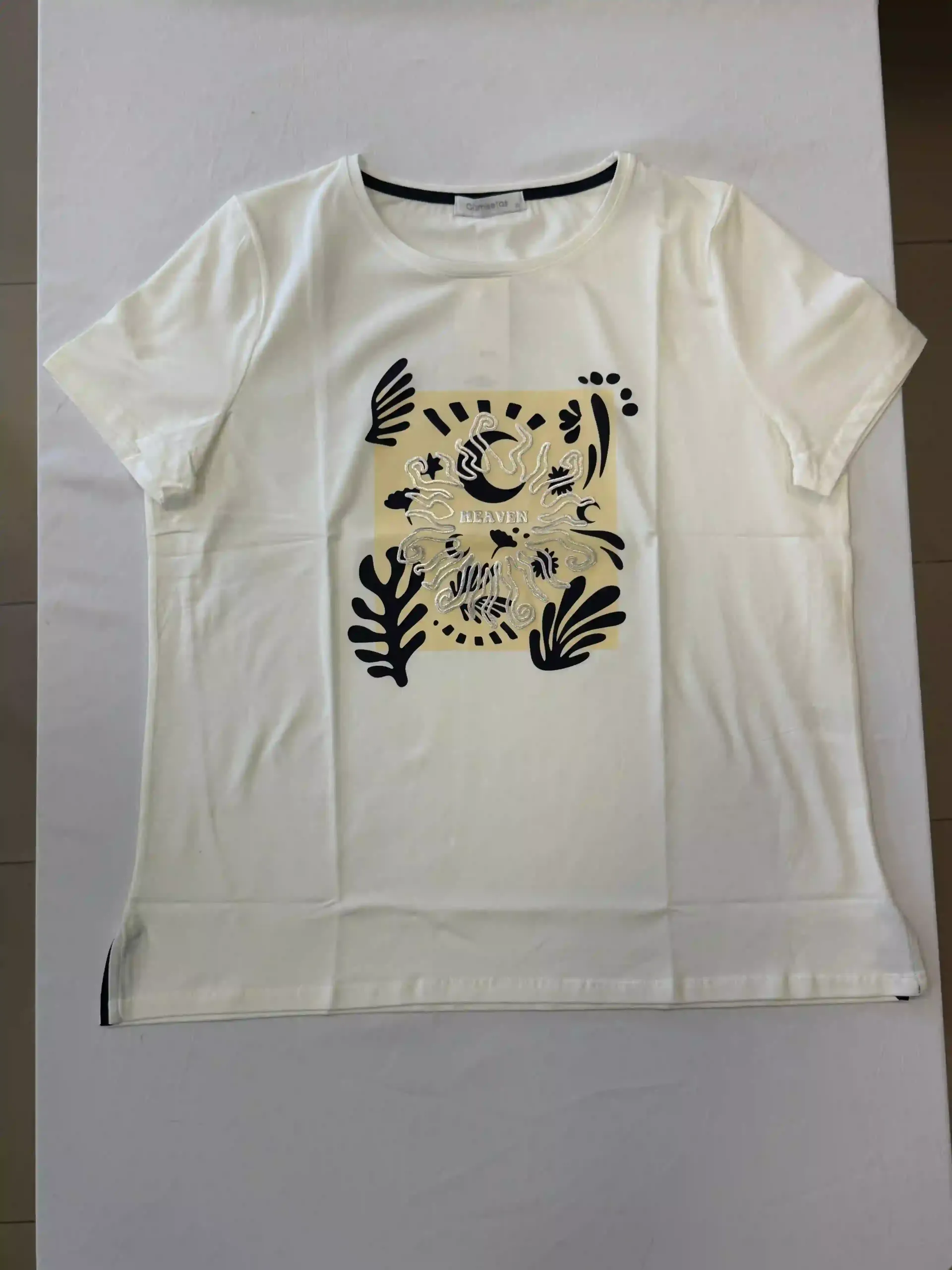 Camiseta blanca con estampado floral y de hojas en color beige centrado en la parte delantera.