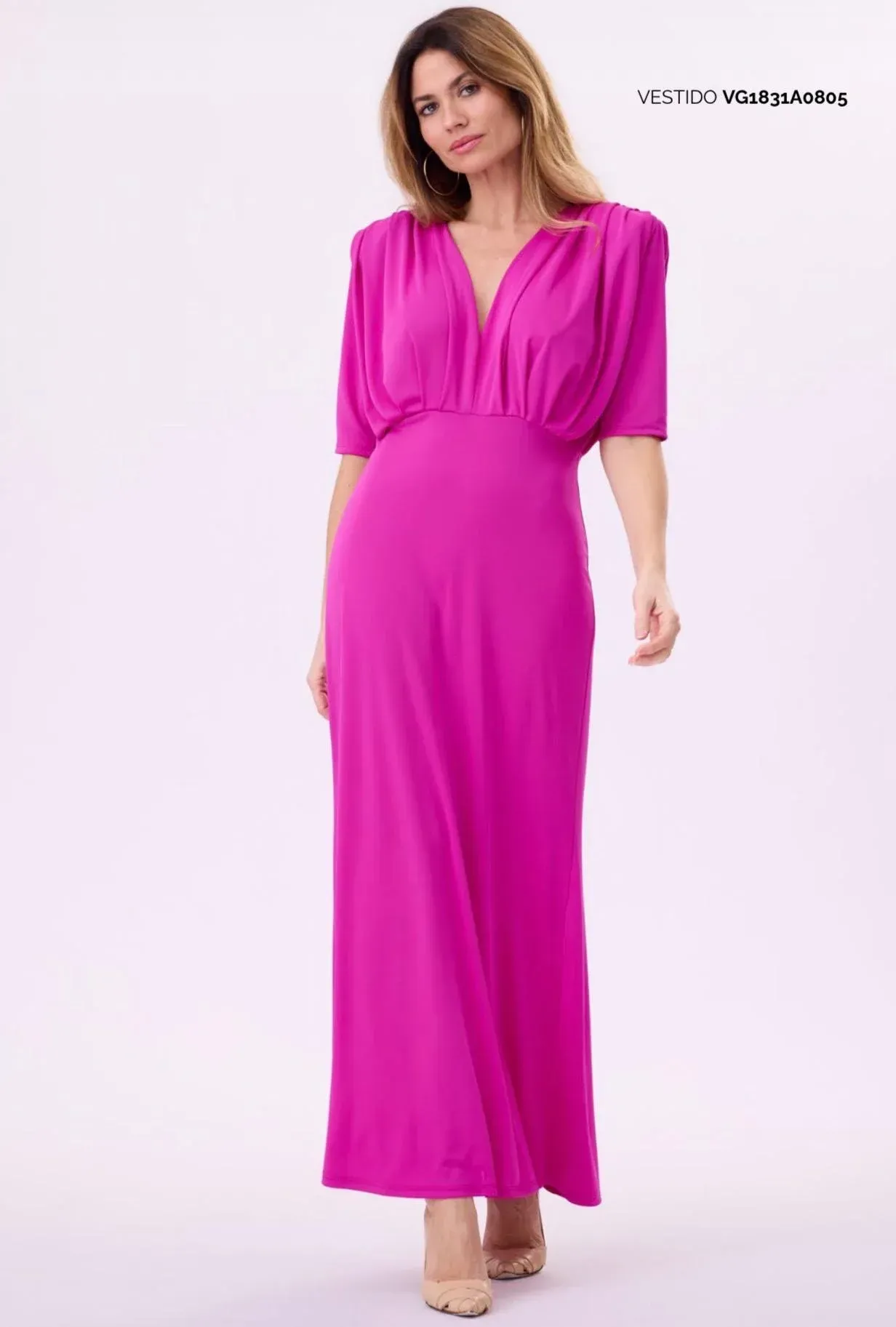 Mujer modelando un vestido largo rosa brillante con escote en V y mangas cortas sobre un fondo blanco.