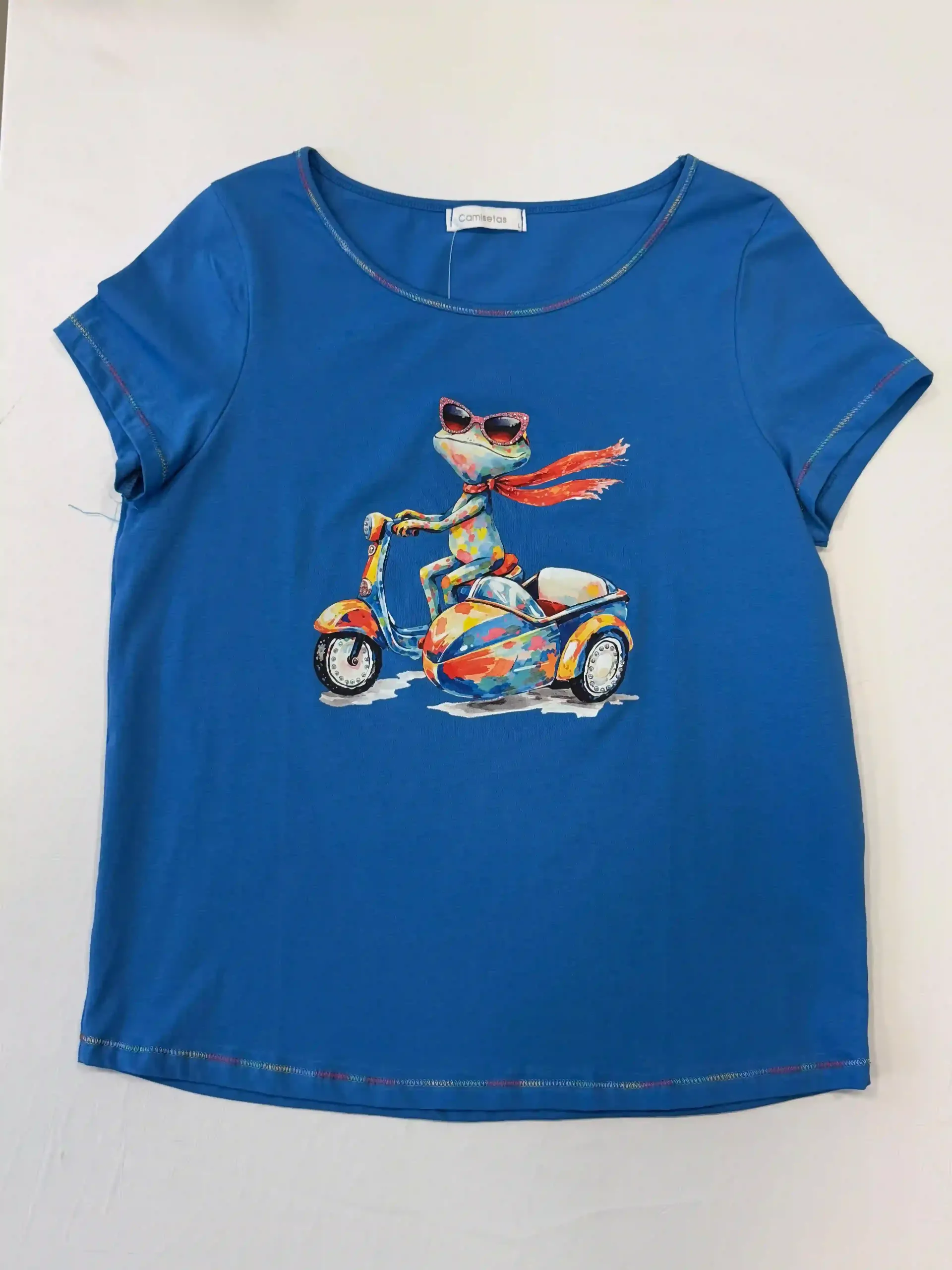 Camiseta azul con un colorido gato de dibujos animados montando en patinete.