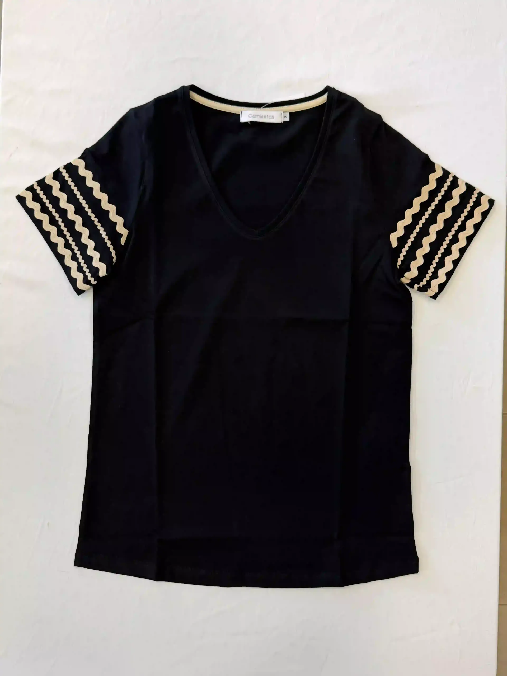 Camiseta negra de manga corta con cuello en V y rayas estampadas en beige y negro sobre fondo blanco.