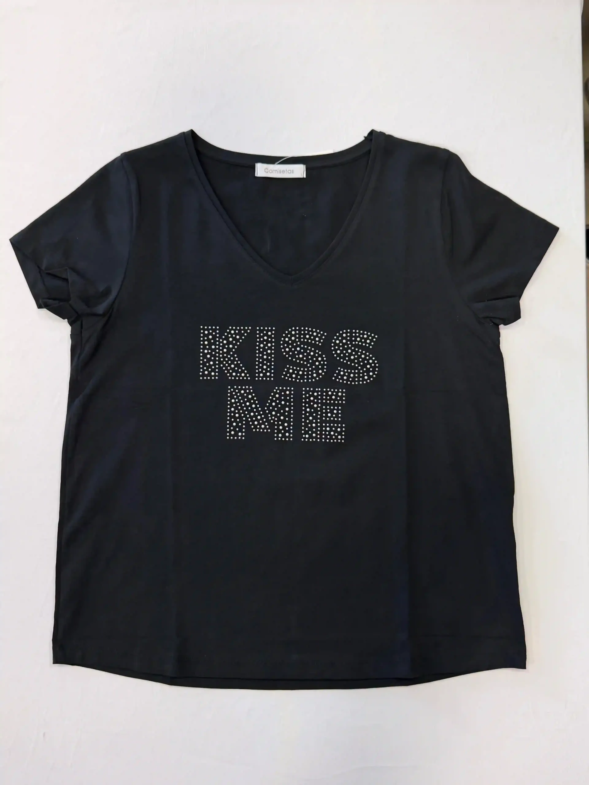 Camiseta negra con texto plateado con tachuelas en la parte delantera, extendida sobre un fondo blanco.