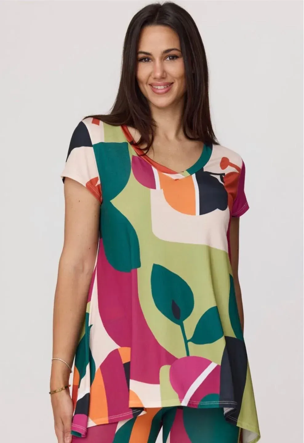 Mujer con una blusa colorida de estampado abstracto sobre un fondo claro.