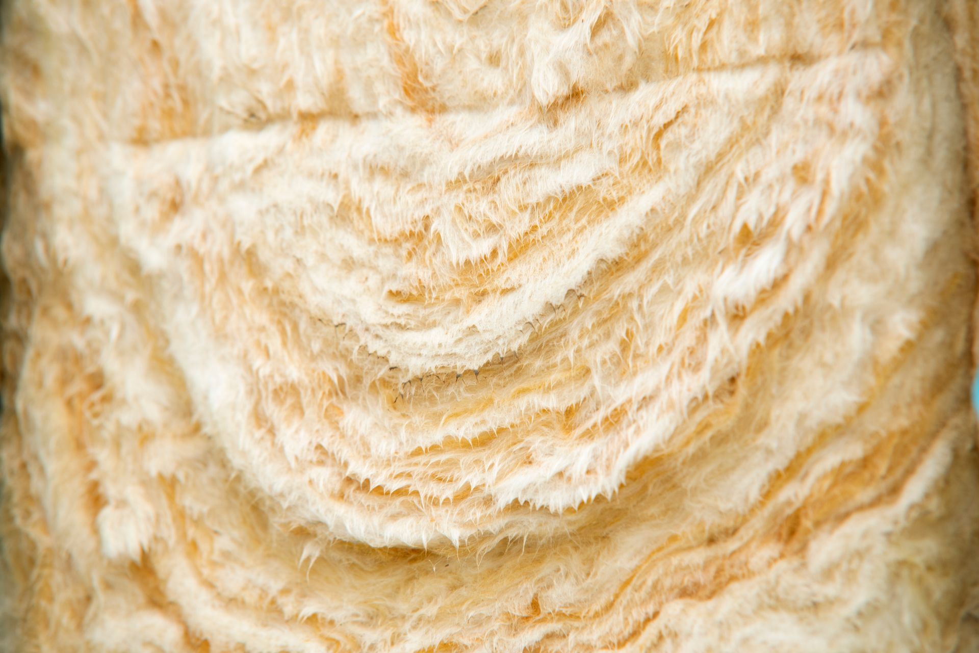 Gros plan sur un rouleau de matériau isolant duveteux de couleur beige.