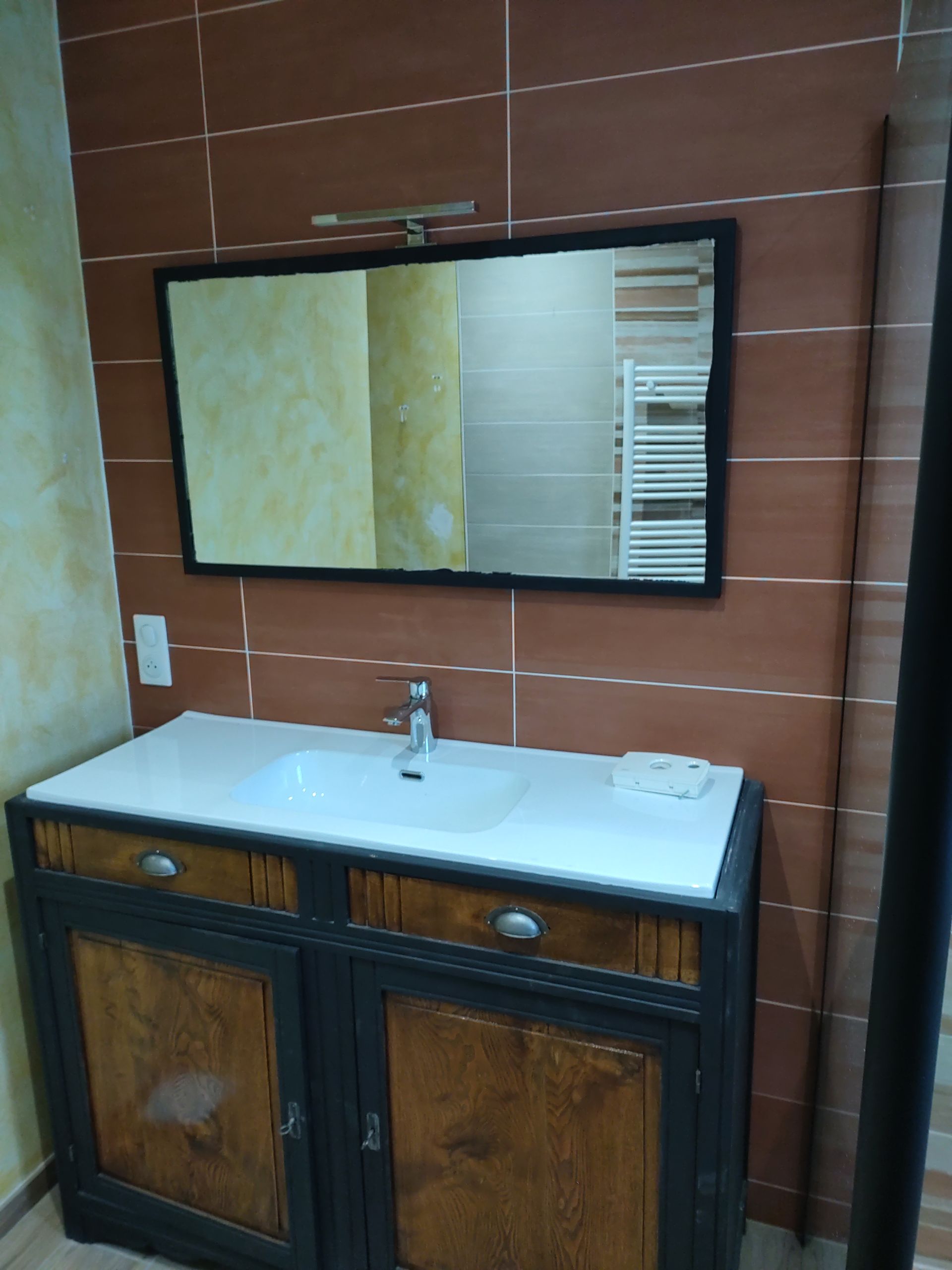 Faïence couleur brique installée sur un mur avec un lavabo et un miroir mural