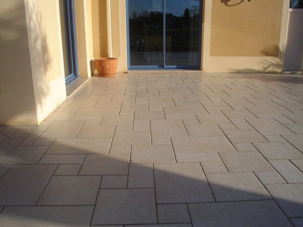 Terrasse dallée devant deux portes vitrées coulissantes