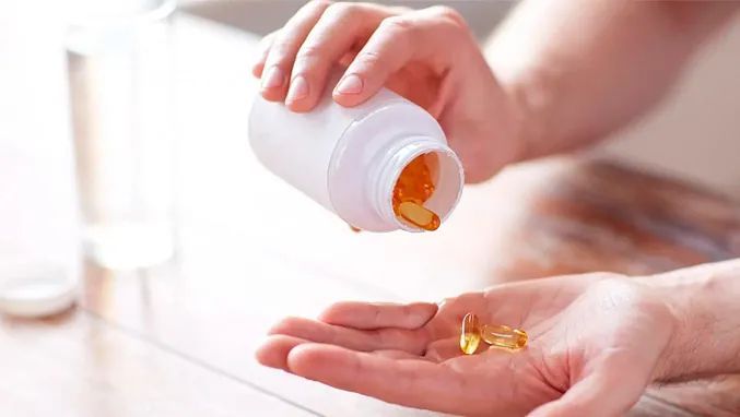 Una persona está vertiendo una botella de pastillas en su mano.