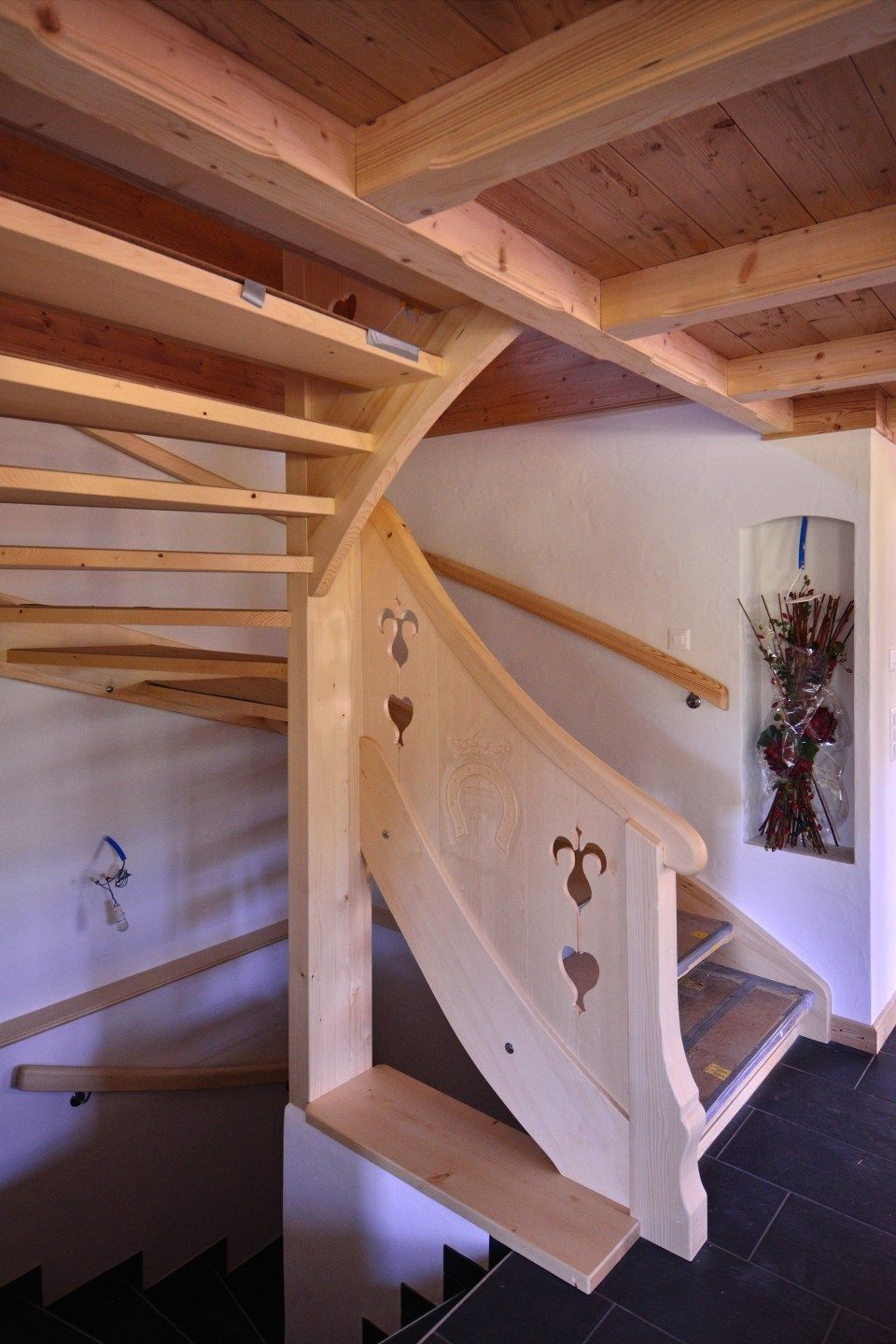 Un escalier en colimaçon en bois dans une pièce avec un tableau sur le mur.