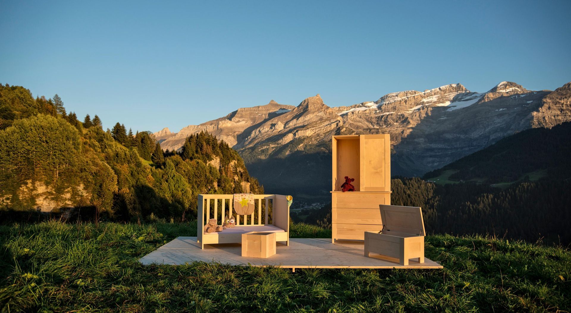 Une table et des chaises en bois sont posées dans un champ avec des montagnes en arrière-plan.