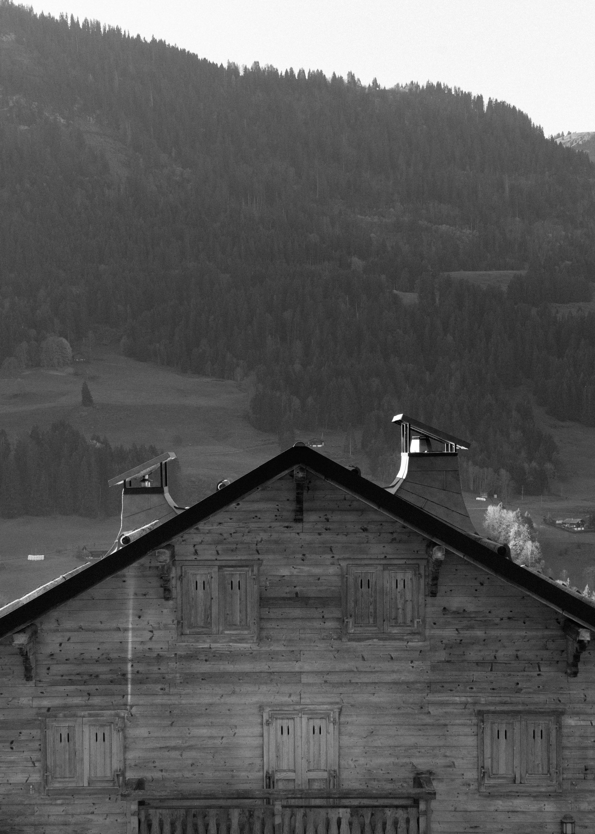Une photo en noir et blanc d'une maison avec des montagnes en arrière-plan