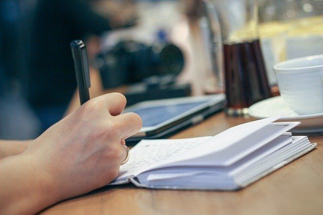 Una persona está escribiendo en un cuaderno con un bolígrafo.