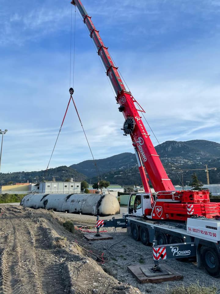 une grue soulevant une moitié de tuyau industriel, d'un autre angle